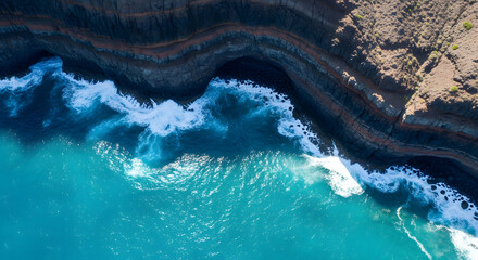 Aerial view of stratified coastal cliffs meeting turquoise Atlan
