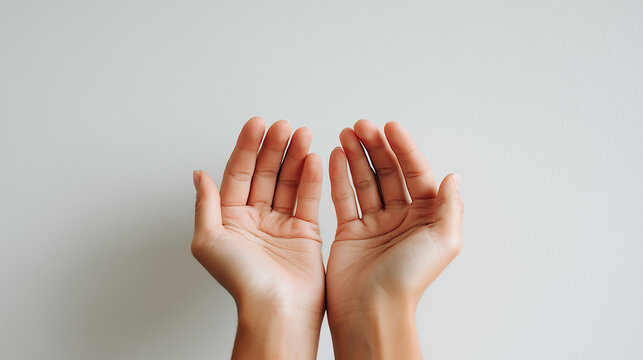 Close up of open human hands with palms facing up against a neutral background as symbol of care, support and hope.