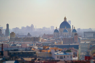 Naklejka premium St Petersburg Russia. Aerial view of building roofs and Holy Trinity Izmailovo Cathedral lit by soft sunlight in the center. Focus at the cathedral. Tilt shift effect and soft filter applied