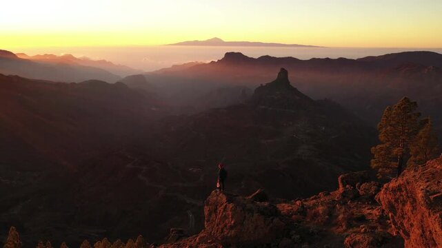 Person Standing on Mountain Peak at Sunset