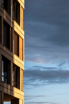 Minimal urban architecture detail showing corner of modern building facade with window lines at dusk under clouded sky creating copy space background