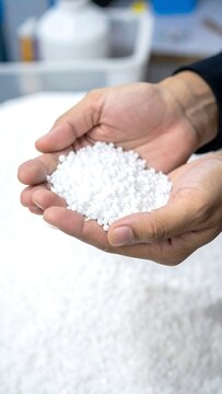Hands hold pile of white pellets, material background