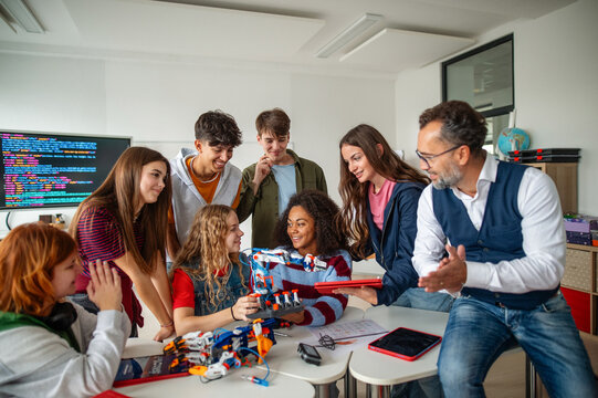 Diverse high school team building robotic arms during science class.