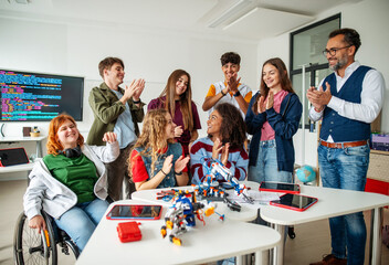 Group of high school students celebrating successful experiment with robotic hand.