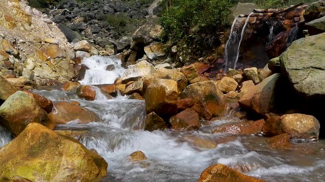 Volcanic freshwater stream flowing through geothermal valley with steam vents at Curug Cikawah, Bogor, West Java, Indonesia.