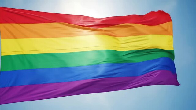 Rainbow flag waving in the blue sky, symbol of pride and diversity