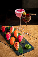 Delight in a stunning arrangement of sushi and colorful cocktails on a wooden table at dinner