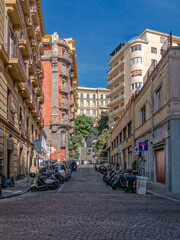 Obraz premium Authentic urban scene in Naples, Italy. Vertical shot of a narrow street with historic apartments, cobblestone road, and traditional Neapolitan life in the Chiaia neighborhood.