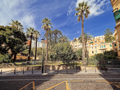 A view of historic luxury residences at parco Margherita, in the chiaia district, naples, showcasing mediterranean palms and decorative italian building..