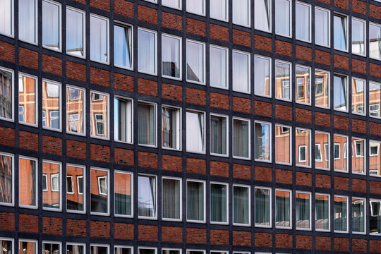 Reflection on brick facade architecture windows in grid pattern in Speicherstadt Hamburg Germany giving modern urban rhythm in daylight
