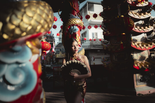 Serious Asian woman in traditional costume with an elaborate headdress for cultural festival celebration. focused dancer preparing for performance in dramatic light