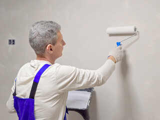 A man is painting a wall with a roller.