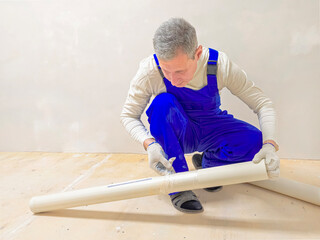 worker is about to paste vinyl wallpaper onto the wall