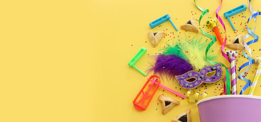 Purim celebration concept (jewish carnival holiday) over yellow background