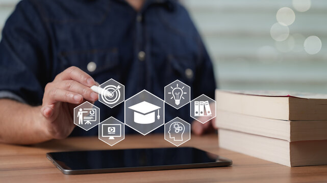 Male student holds white stylus touching digital tablet screen accessing virtual education icons near hardcover book stack representing hybrid learning concept plus future academic success goals