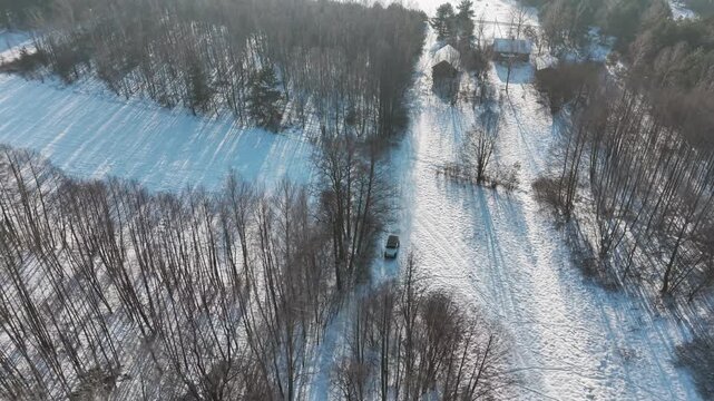 Vehicle driving through snow covered winter scene in Poland, aerial reverse view
