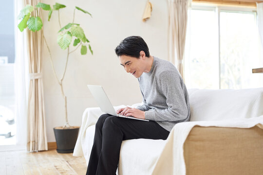 猫背でパソコン操作をするアジア人男性