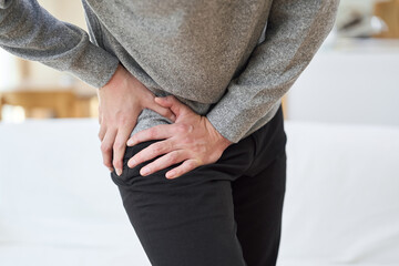 股関節が痛くて苦しむアジア人男性
