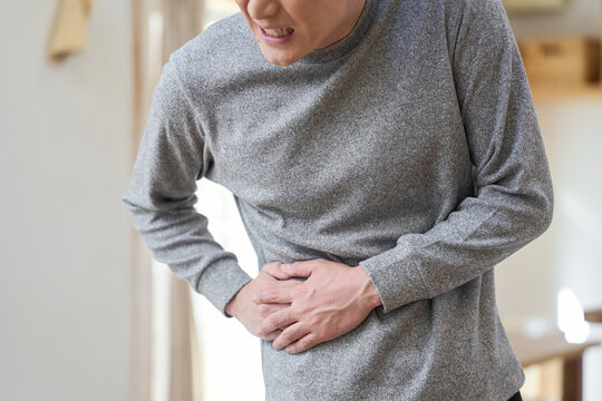 横腹が痛くて苦しむアジア人男性