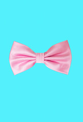 Pink satin bow tie isolated on a light blue background.