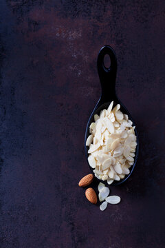Spoon of sliced and blanched almonds on rusty ground