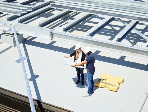 Worker and architect looking at blueprint on construction site