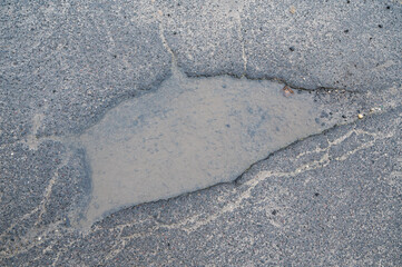 Obraz premium Pothole on asphalt road, puddle, water hole after rain, condition of street in Germany, damaged highway, dangerous surface
