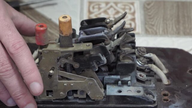 Repair of vintage electrical equipment, Vintage industrial electrical mechanism in action, Close-up of hands pressing a button on a complex retro mechanical device