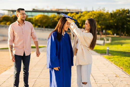 Friends celebrating student on graduation day outdoors