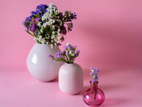 Colorful flowers in vases against pink background