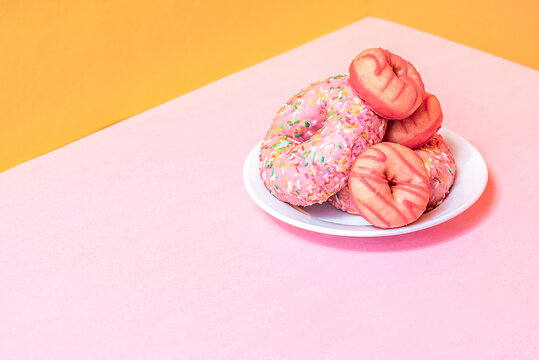 Pink donuts with sprinkles on a white plate