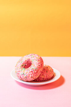 Pink donuts with sprinkles on colorful background