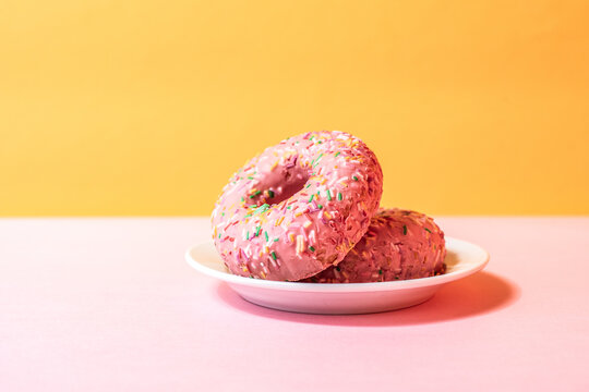 Pink donuts with colorful sprinkles on white plate