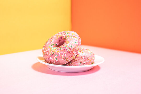 Pink donuts with sprinkles on colorful background