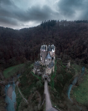 Aerial view of a majestic castle nestled atop a verdant hill, its ancient stones contrasting against the dark, moody sky, Bavaria, Bavaria, Germany.