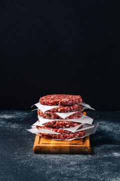 Veal burger patties stacked on wooden board