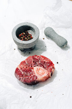 Veal shank with spices and mortar on white background