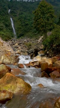 Vertical view Volcanic river flowing through geothermal mountain valley with active crater and in the distance the Curug Cikawah waterfall, Bogor, West Java, Indonesia.