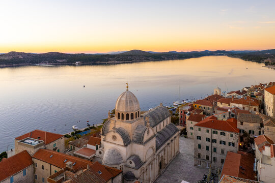 Aerial view of the majestic Cathedral of St. James with its stone facade contrasting against the calm, reflective waters, Sibenik, Croatia.