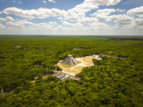 Aerial view of ancient Mayan architecture amidst vibrant green jungle canopy, dominated by the imposing pyramid of Kukulcan, Chichen-Itza, Yucatan, Mexico.