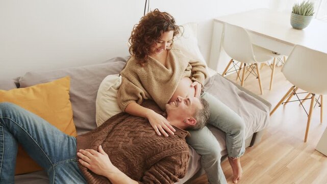 Affectionate pregnant Latin couple relaxing on a couch
