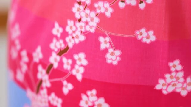 Close-up of vibrant floral fabric featuring cherry blossom patterns. Represents cultural heritage and artistic textile design