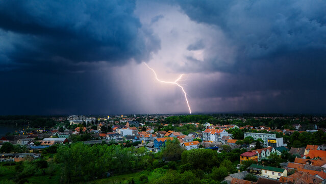 Aerial view of a jagged lightning bolt illuminating the horizon over the cityscape, a stark contrast to the dark, brooding storm clouds above, Sremska Mitrovica, Vojvodina, Serbia.