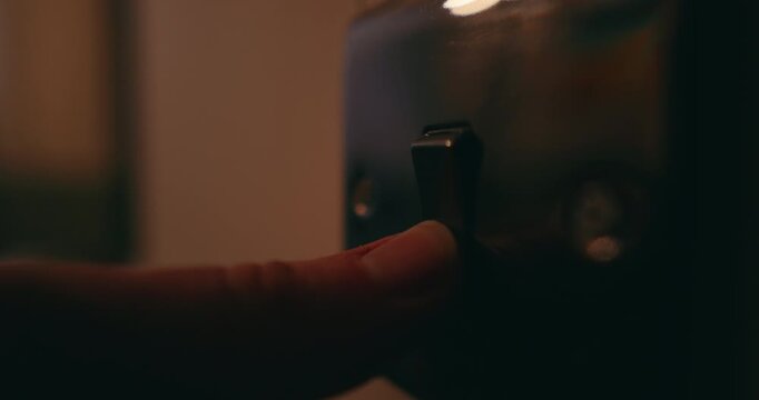 Close-up of hand flipping light switch indoors, adding a bright ambiance