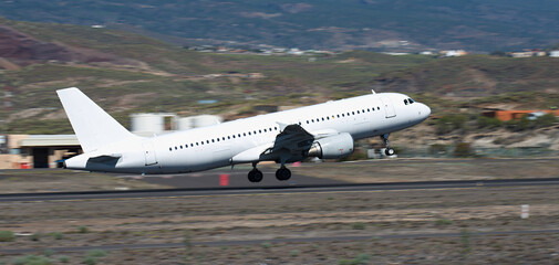 White transport plane takes off. Take-off on the runway. Panning shot, background becomes blurred