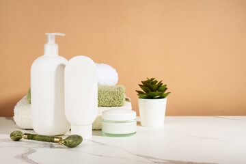 Skin care products in the bathroom. Face cream, serum bottle, jade roller and stack of towels. © nadianb