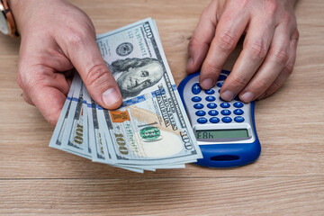 Top View of Man in Suit Using Blue Calculator and Counting Dollar Cash for Financial Planning