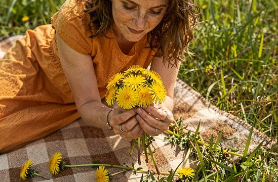Woman holding bouquet of dandelions in meadow