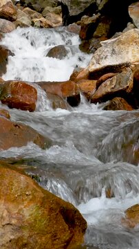 Vertical view Seamless Loop Fast flowing freshwater stream through volcanic geothermal terrain at Curug Cikawah waterfall, Bogor, West Java, Indonesia.
