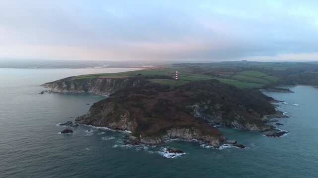 Aerial view of the red and white striped Gribbin Head Daymark standing tall amidst the dark green landscape and light blue sea, Fowey, England, United Kingdom.